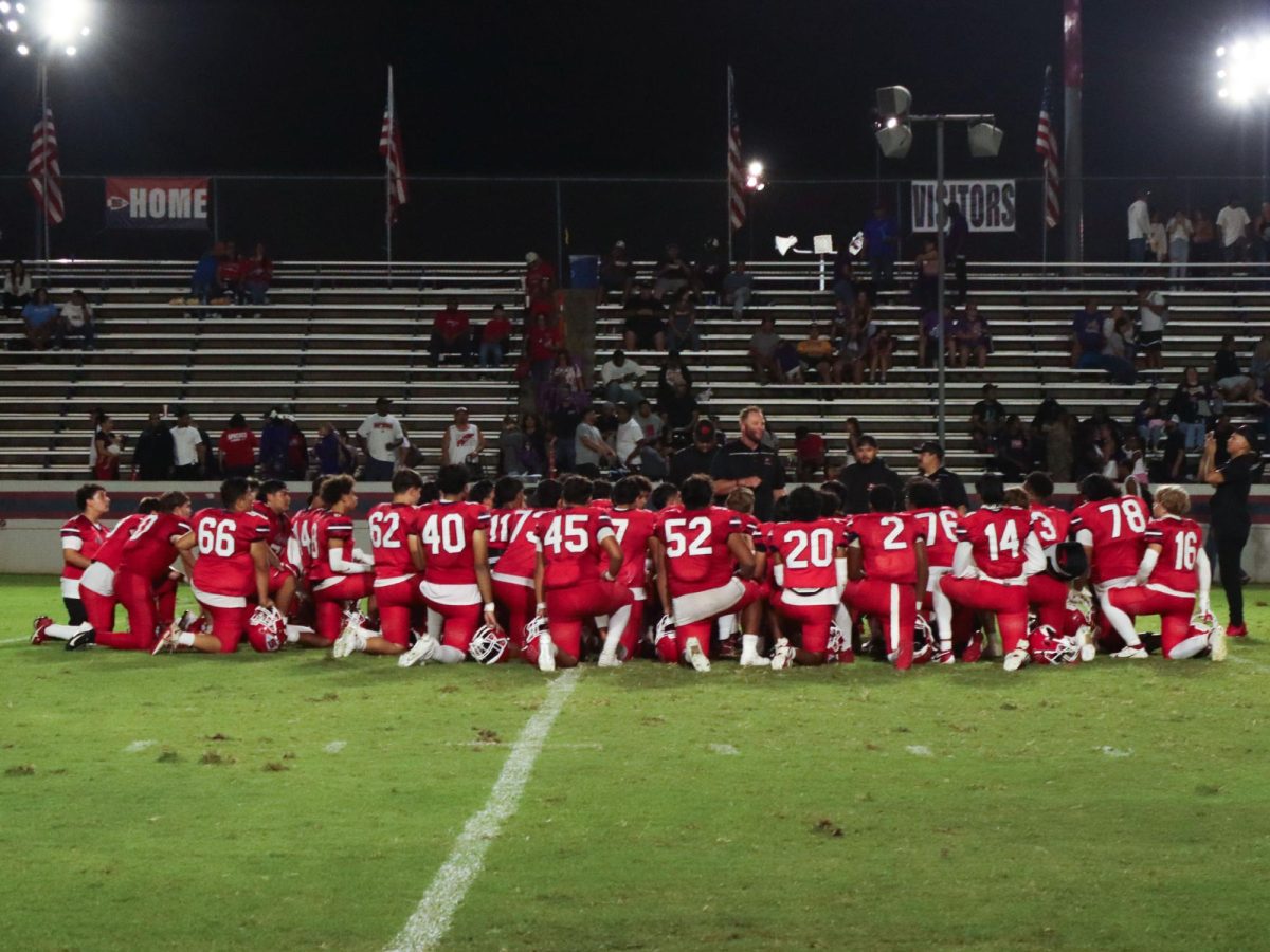 After winning their first home game. the team gathers on the field, kneeling to take in the big win.