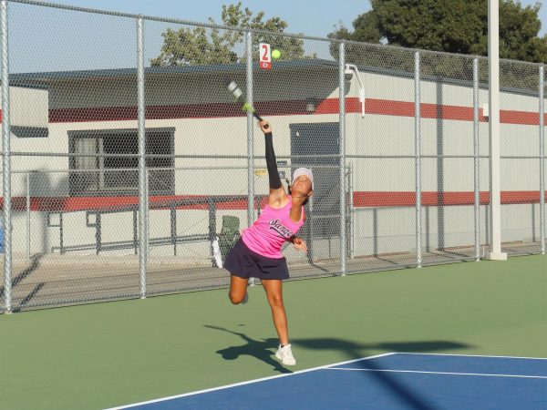 Haley Delgado reaches to hit the tennis ball. 