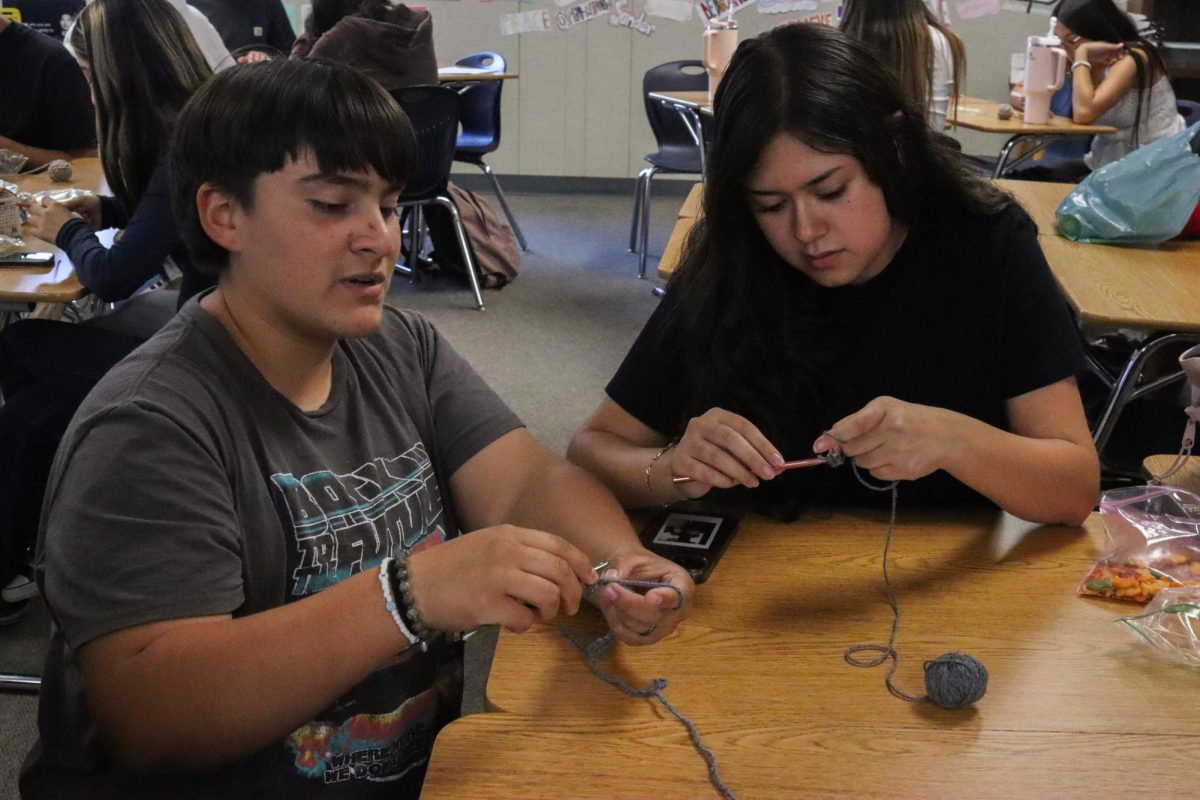 Nick Madrigal guiding a club member through a crochet piece.